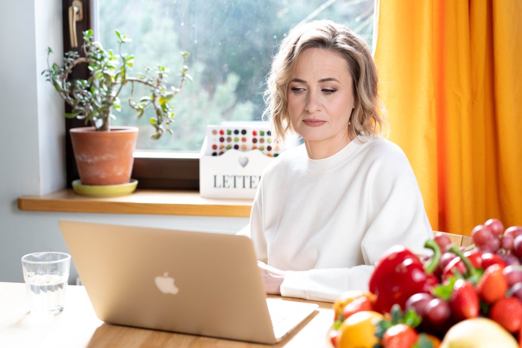 Dietetyk Katarzyna Bychowska-Koczergo pracuje przy laptopie, układając diety online dla pacjentów z Grodziska Mazowieckiego i Pruszkowa.